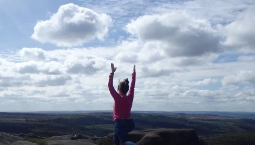 Person standing outdoors beneath a dramatic cloudy sky