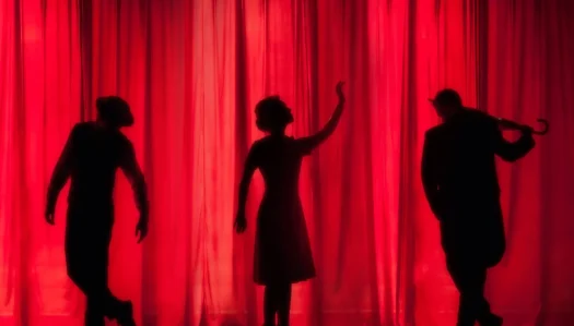 Silhouettes performing on stage behind a red curtain
